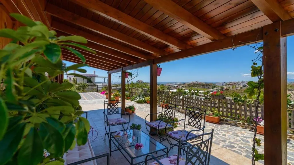 Porche cubierto de Casa Alegría con zona de asientos y vistas hacia la costa