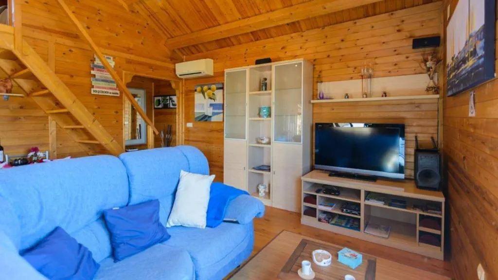 Salón interior de Casa Alegría, con sofá, televisión y acabados en madera